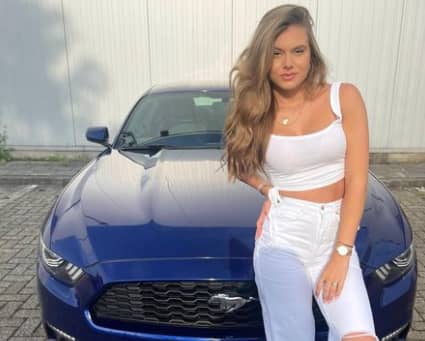 Nina Houston stands in front of her luxurious car